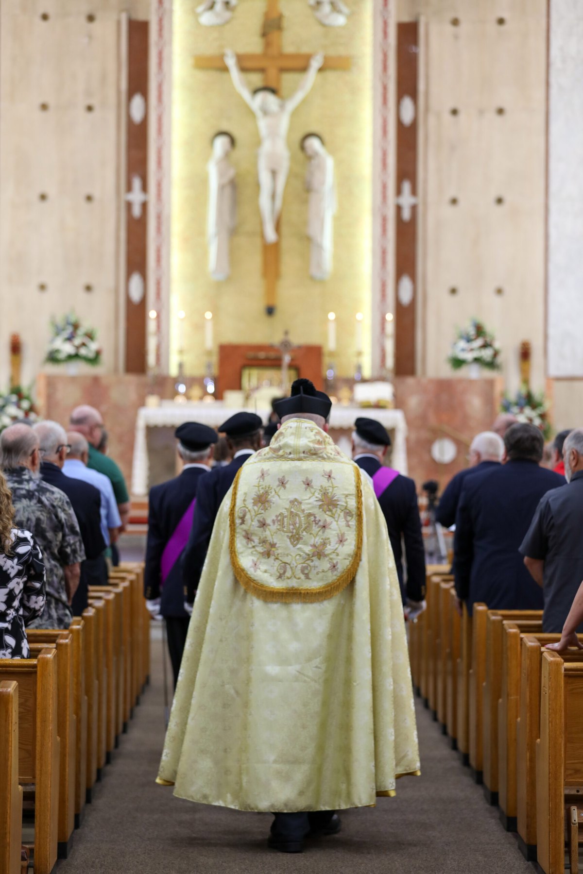 Priest in a gold cope processes down the center aisle